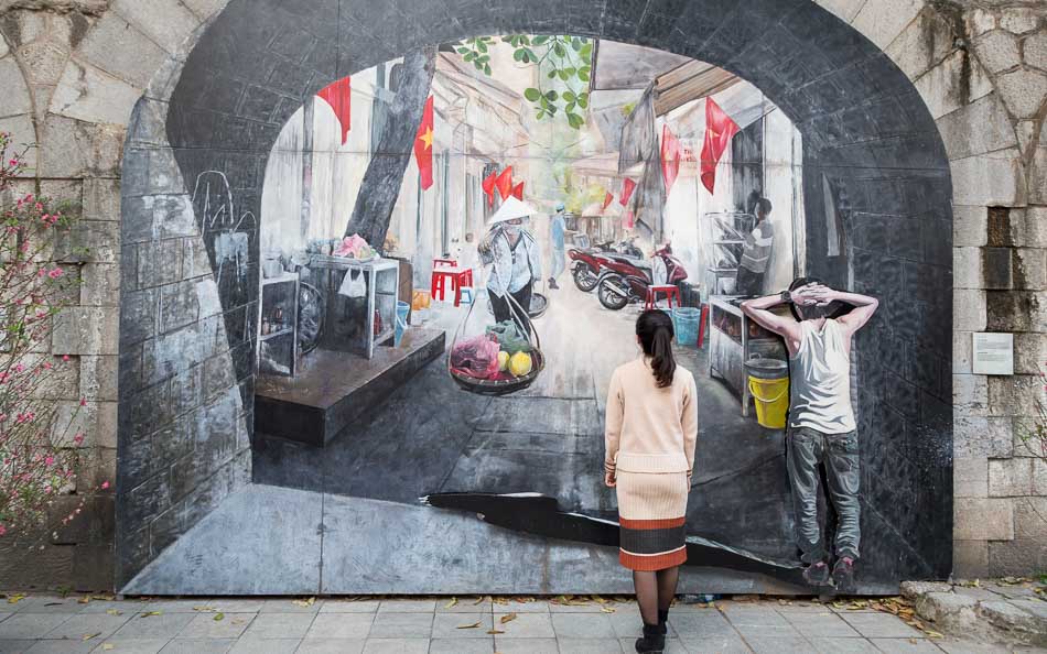 Mulher fotografando os murais da rua Phung Hung