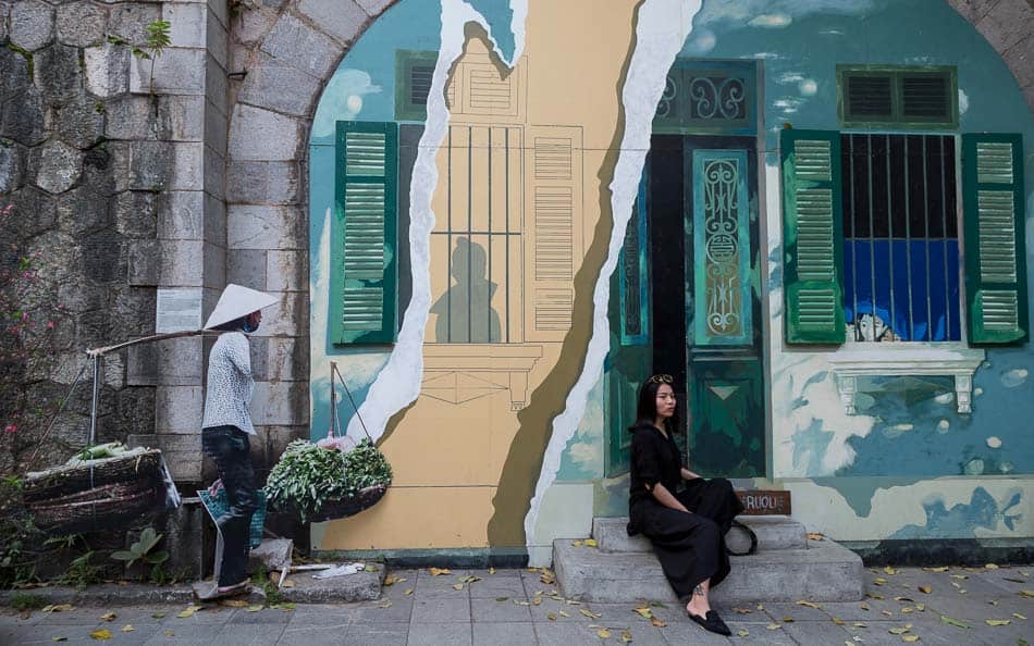 Mulher posando em frente a mural na rua Phung Hung em Hanoi